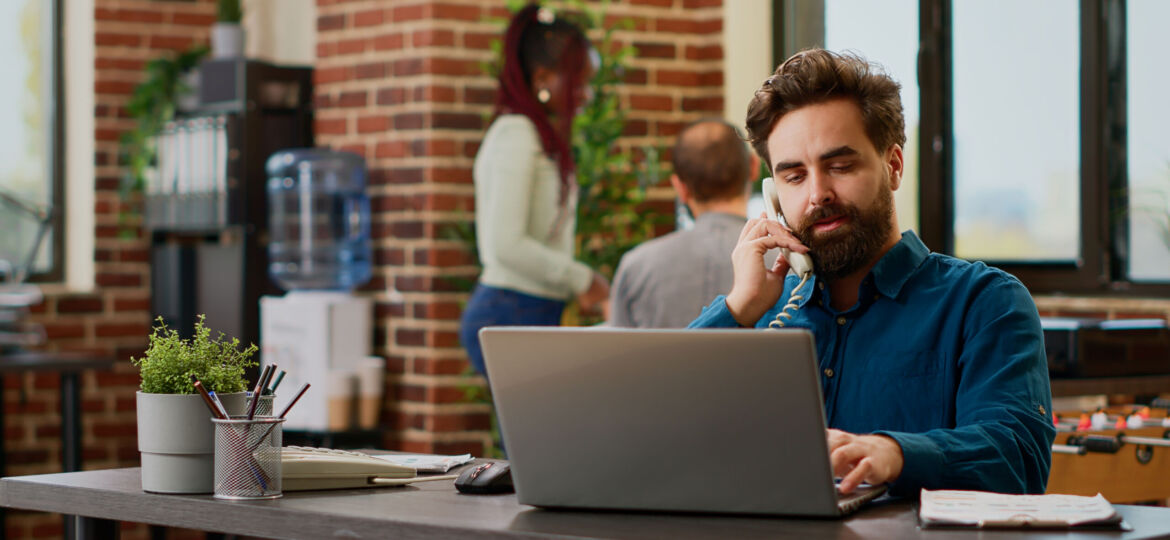 Company employee answering landline phone call at corporate job