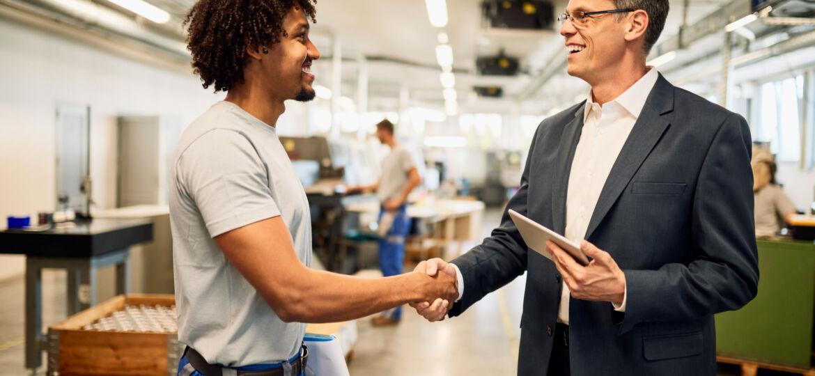 Happy manager and African American steel worker shaking hands in